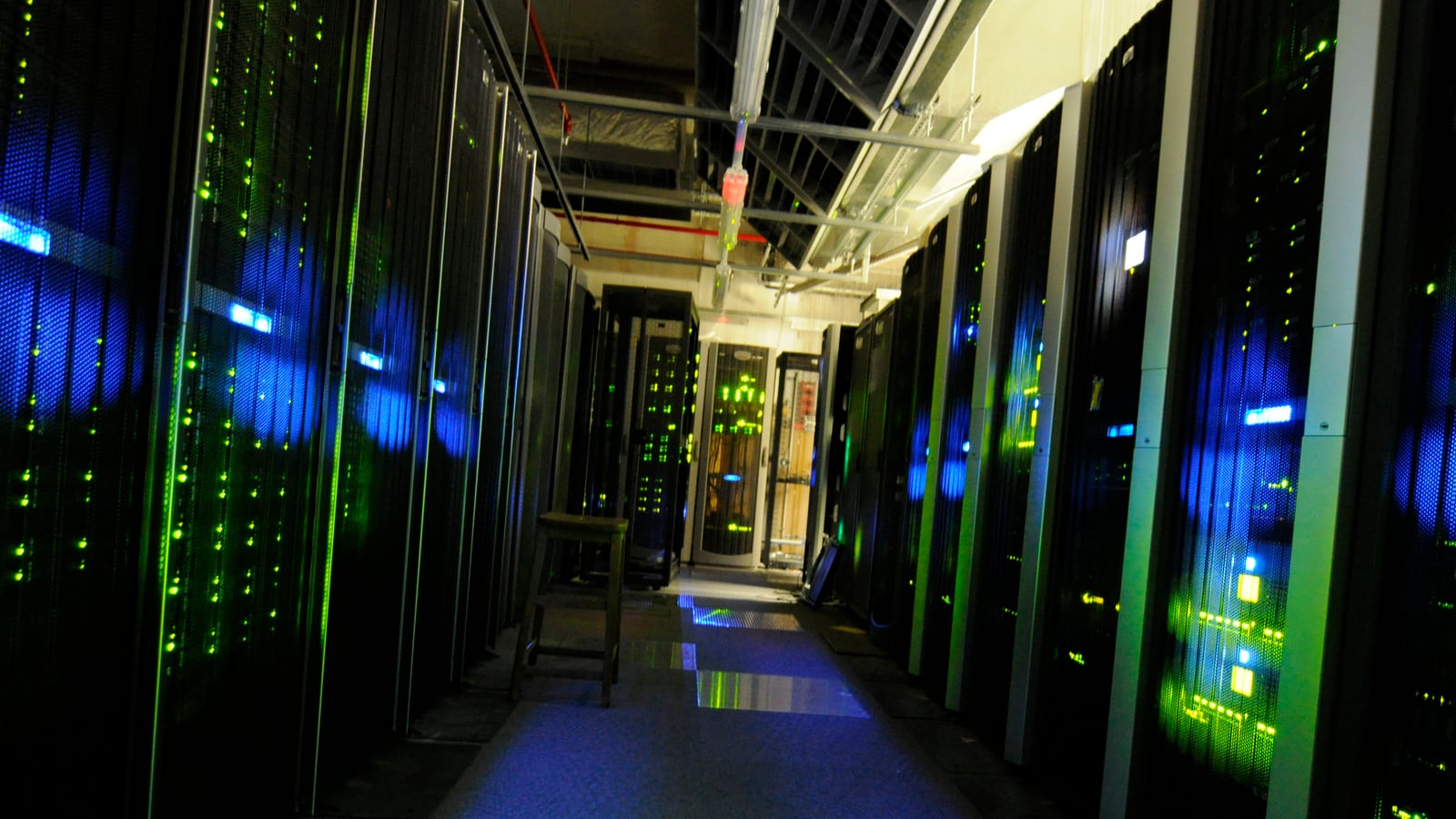 Pasillo de un centro de datos con armarios de servidores y luces verdes y azules