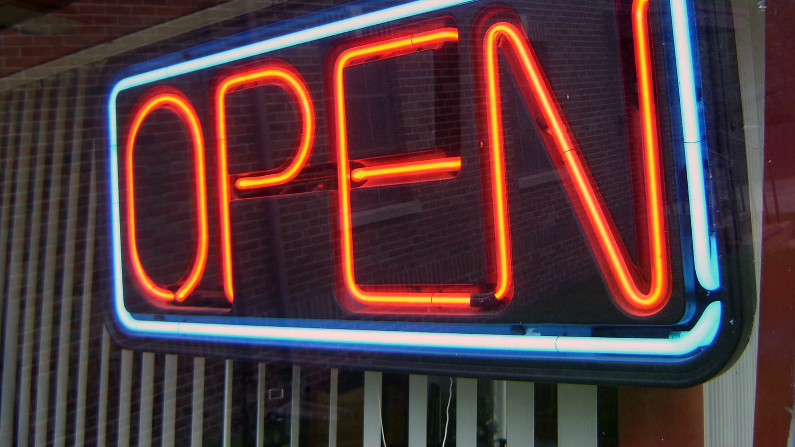 Letrero de neón con la palabra OPEN en rojo y borde azul